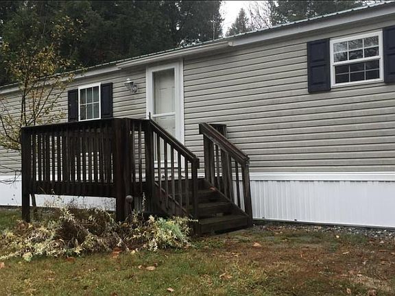 Home has beautiful flower beds surrounding the deck, apple tree and to the left a large metal separate storage shed