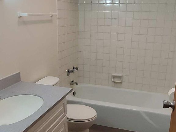 Well-lit bathroom with new vanity and linen closet behind bathroom door.