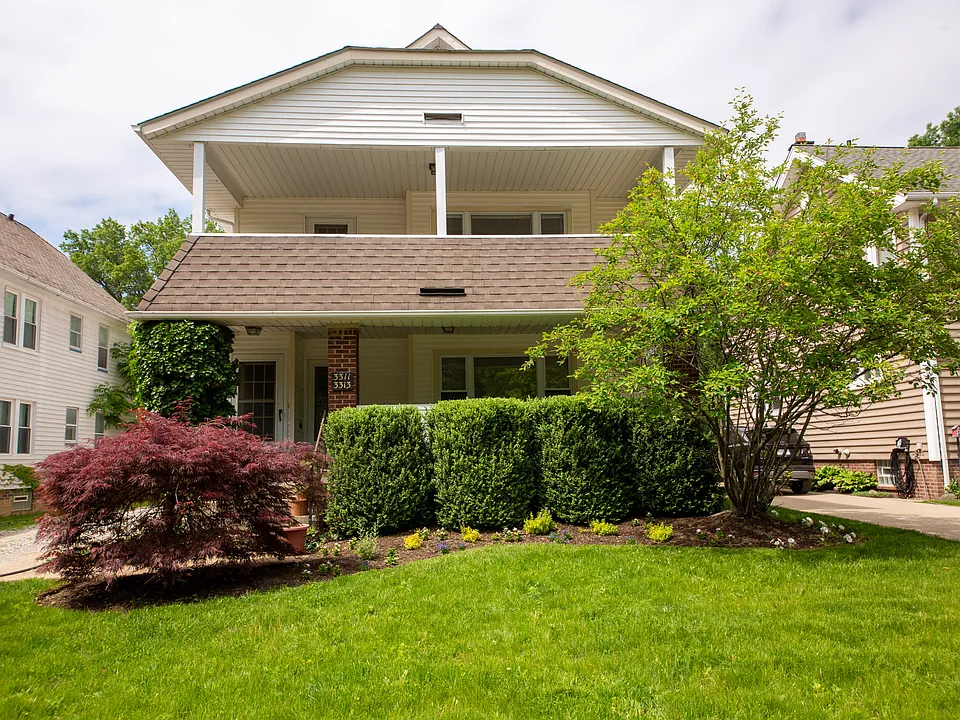 Charming Cleveland Heights triplex featuring classic architectural character, mature landscaping, and an inviting covered front porch