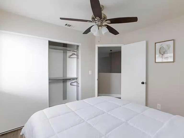 Bedroom with a ceiling fan, open reach-in closet with shelving, and neutral finishes for easy furnishing.