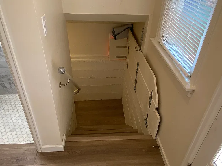 Stairs to laundry room with dog walkway to dog door folded up.