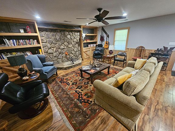 Inviting shared living room with a stone fireplace feature, built-in shelving, and ample seating around a central coffee tabl
