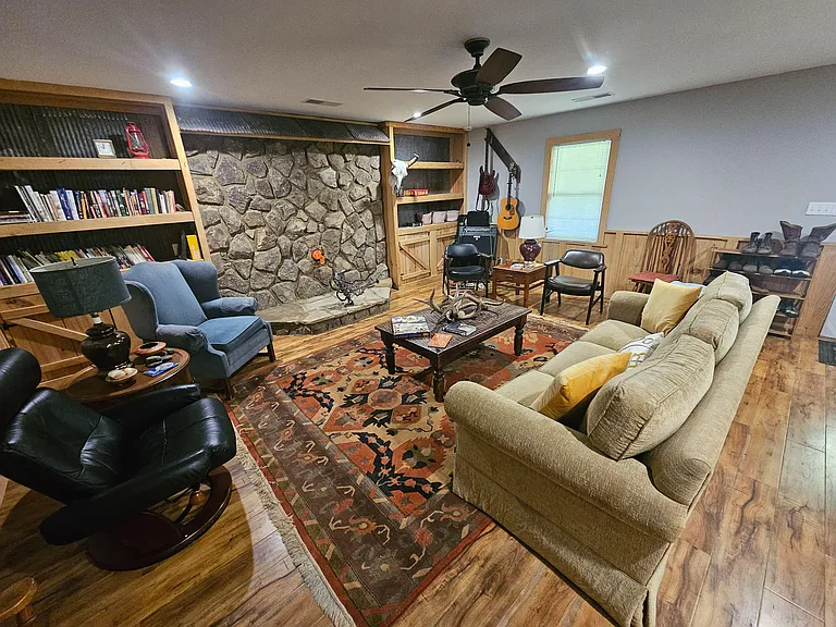 Inviting shared living room with a stone fireplace feature, built-in shelving, and ample seating around a central coffee tabl