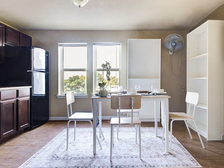 Eat-in kitchen area with a dining table, ample cabinetry, and a full-size refrigerator, plus large windows for daily light.