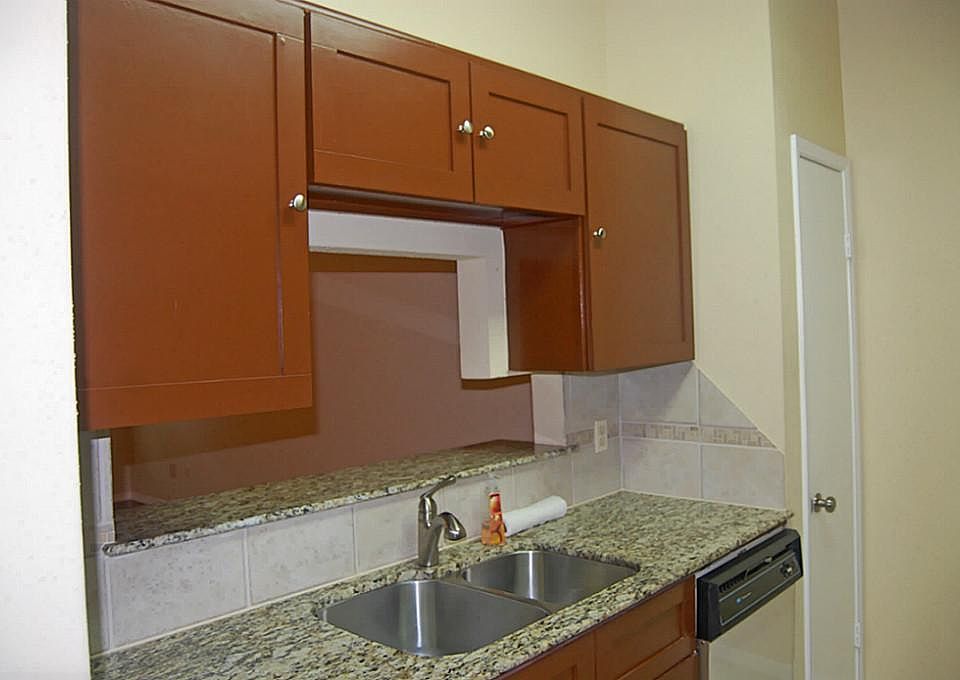 Granite counters in kitchen. Elegant, updated cabinet fronts, fancy faucet, stainless steel sink.