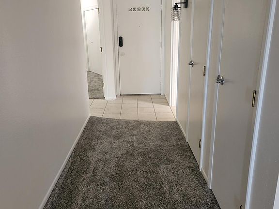Hallway showing the entry door at center and guest bedroom on the left. You'll notice the two closets on the right.