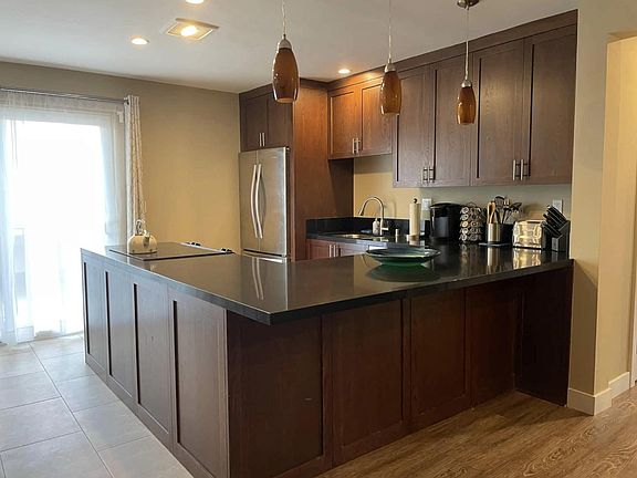 The kitchen has granite counter, stainless appliances, and wood cabinets. Missing from the photo are bar stools