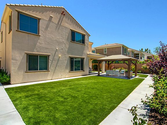 Artificial turf , new landscaped yard with plants on a drip system .
