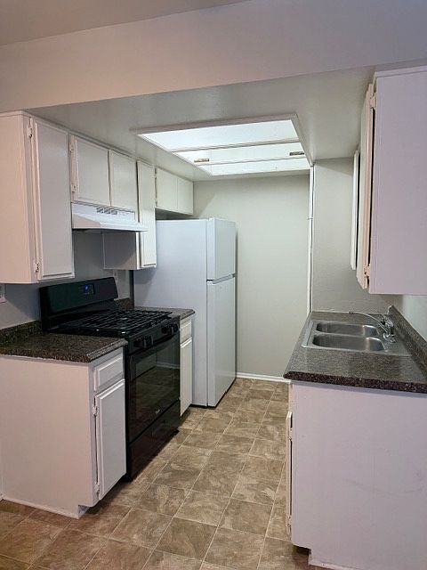 Galley kitchen with new stove and new refrigerator