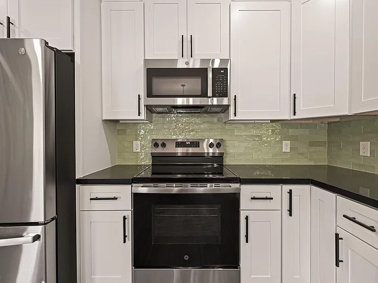 Updated kitchen with stainless steel range, built-in microwave, ample shaker cabinetry, and generous counter space.