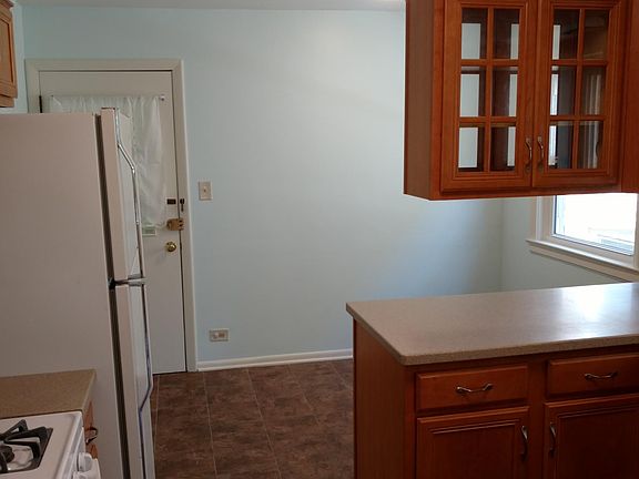 looking northeast in the kitchen into the eating area. The back door leads to a stairway to the outside door and basement where there is laundry.