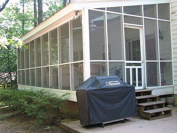 Back of home is screened in porch, patio and lovely tree lined fenced yard