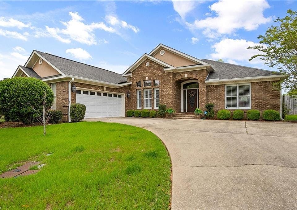 Ranch-style home featuring a front yard, a garage, brick siding, and concrete driveway