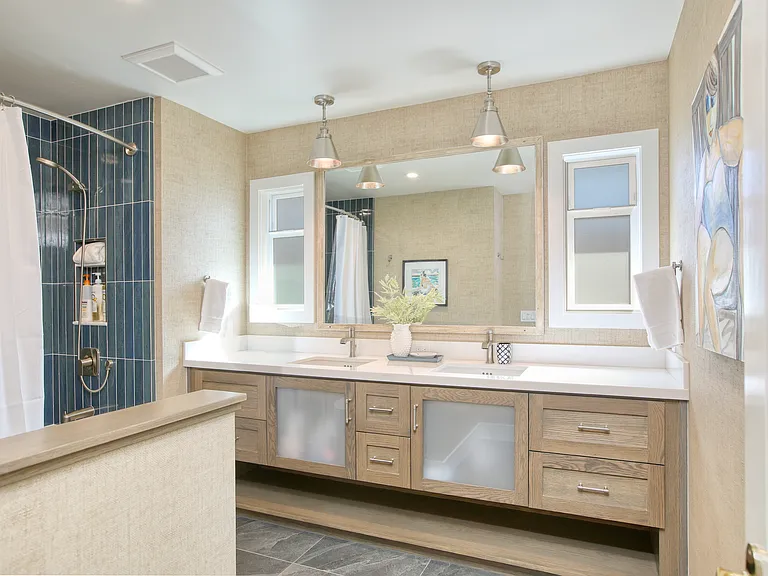 Freshly updated, beach-inspired bathroom with custom cabinetry, a double-sink vanity, and a newly tiled tub and shower combination. Light, airy, and thoughtfully designed to capture a relaxed coastal feel for starting or unwinding after a day by the ocean