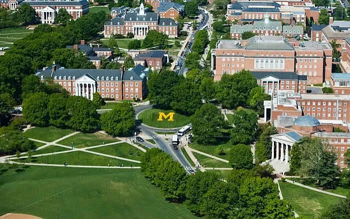 Expansive outdoor grounds with mature trees, landscaped lawns, and wide walkways connecting multiple buildings.