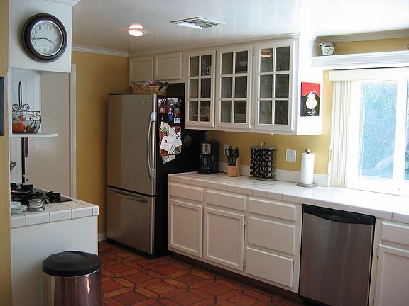 Bright kitchen has glass cupboards and kitchen sink looks out to pool/spa.
