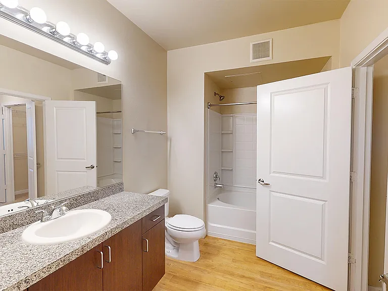 Apartment bathroom with large soaking tub and wood-style flooring.