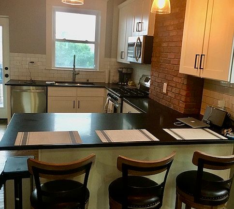Open-concept kitchen featuring granite countertops, stainless steel appliances, and ample bar seating.