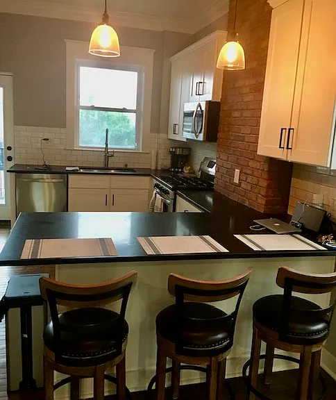 Open-concept kitchen featuring granite countertops, stainless steel appliances, and ample bar seating.