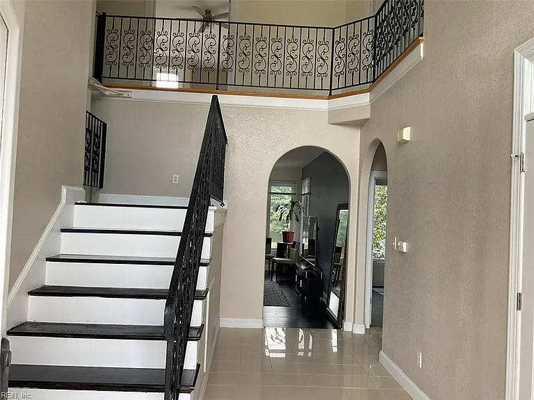 Enter house to Foyer with wrought-iron railings and stairs to 2nd level. One archway leads to Family room, and the other leads to two (2) first-floor bedrooms and a full bath.