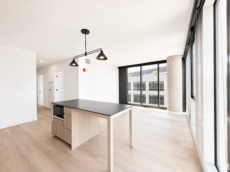 Open kitchen and dining area at Stead 220 in Fulton Market with a center island and breakfast bar, pendant lighting, and floor-to-ceiling windows filling the space with natural light.