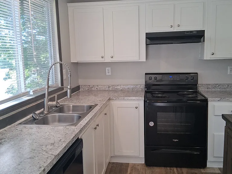 Spacious kitchen offering island eating, stove, fridge, and dishwasher with a double sink and wonderful counterspace under bright sunlight for cooking.