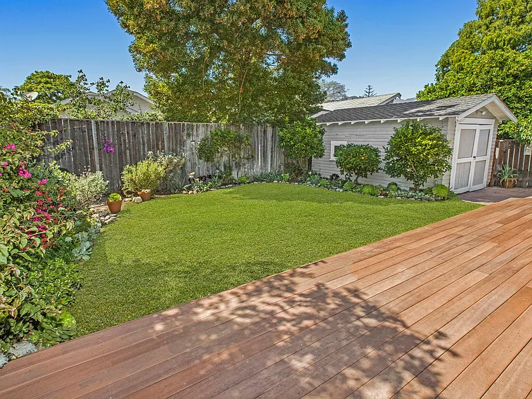 Backyard deck, grass area, and detached garage stocked with beach supplies and bikes