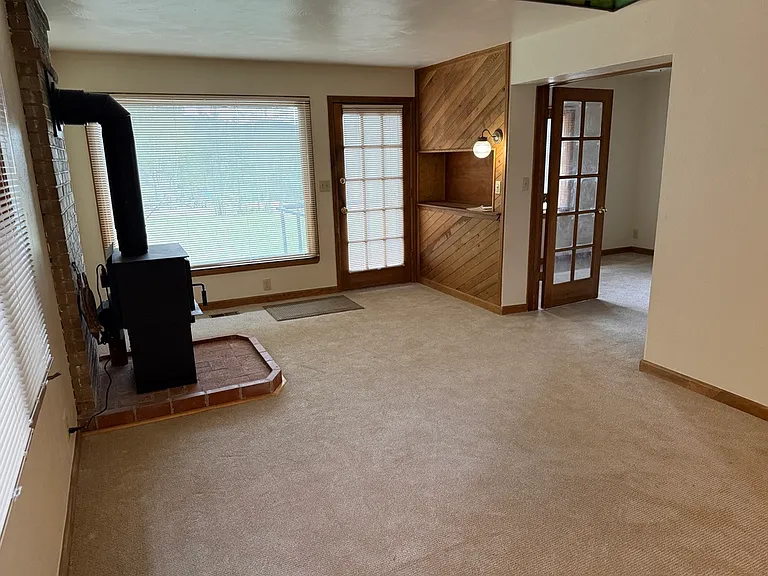 Living room, wood stove/hearth, entertainment shelf, double door entry to den/office (picture taken from dining area)