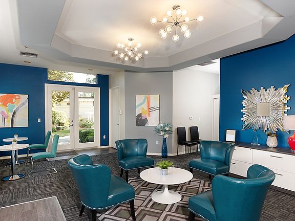 Carpeted clubhouse with modern lounge chairs and tables.