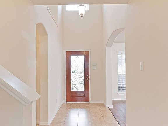 A dramatic two story foyer flanked by arched openings with a large art niche has ceramic tile floors