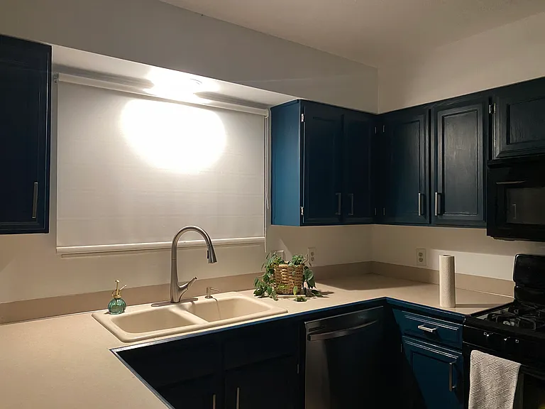 Evening kitchen view - adorable cabinet color, new faucet with sprayer, nice roller window coverings.
