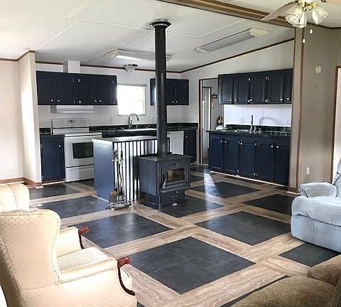 The center of the house is a large Great Room that encompasses the kitchen, dining room and living room. The kitchen island is backed by a fully functional, free standing wood stove with a glass door to view the fire.