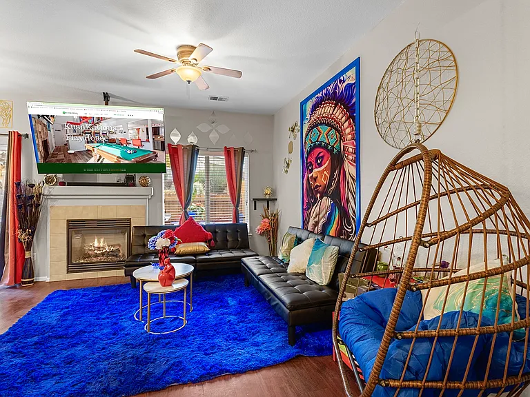 Spacious and eclectic living room with a cozy fireplace, comfortable seating, and a unique hanging chair. Perfect for relaxing and unwinding.