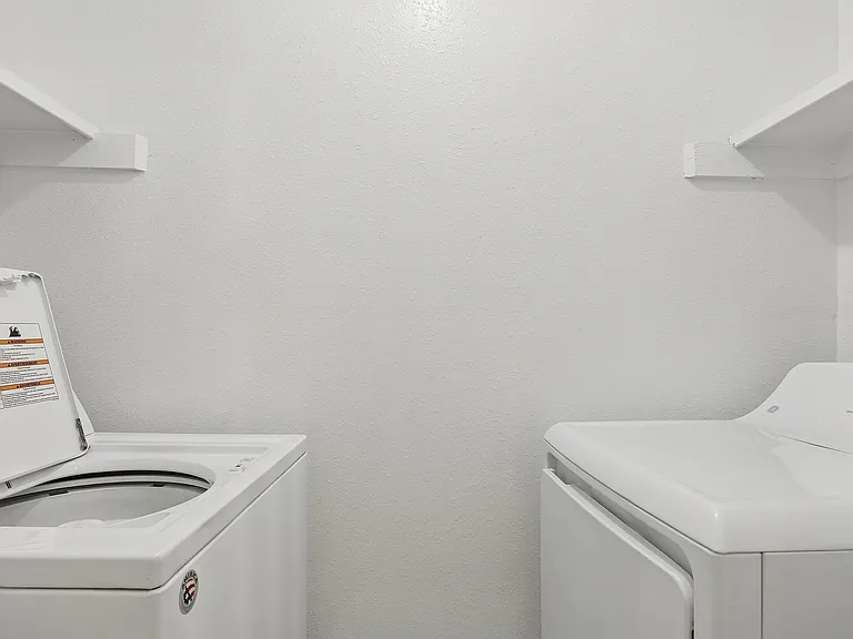 A full-size washer and dryer is shown in the laundry room of an apartment.