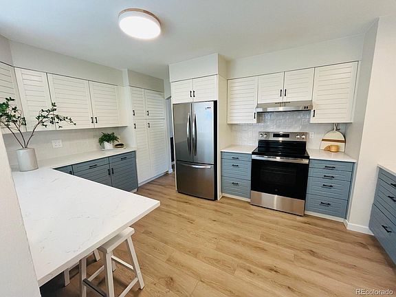 Kitchen w/refrigerator, stovetop, dishwasher, coffeemaker, microwave, cookware, glasses, mugs, plates, bowls, silverware.