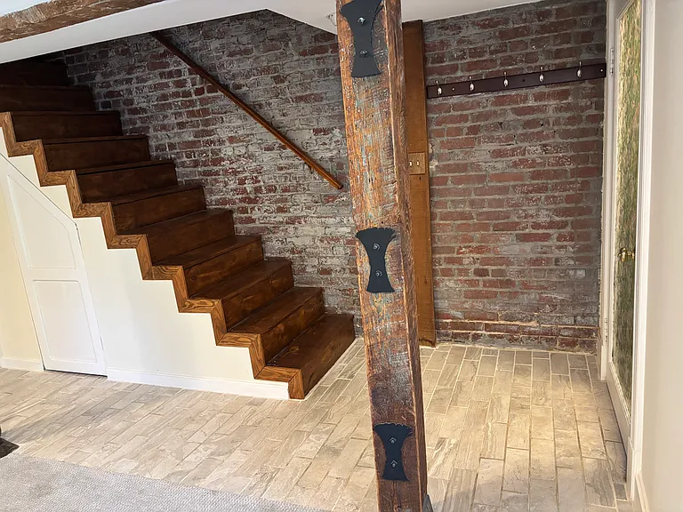 Apartment entrance coat hook area and steps as shoe and letter drop. Steps lead to upstairs apartment but access has been closed with a door covered with an acoustical tile board.