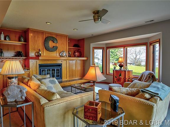 The living room has a beautiful fireplace, with a large flat screen tv behind the roll doors.