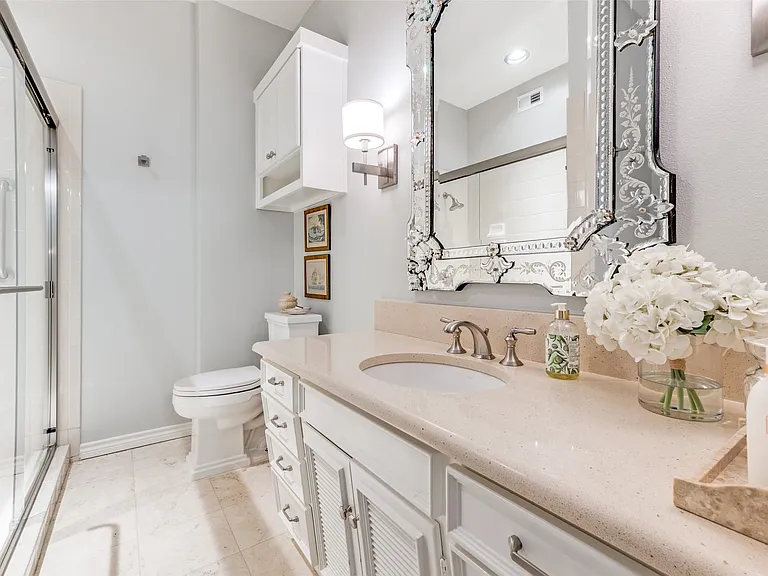 Bathroom featuring a glass-enclosed shower, single vanity with light-colored countertop, decorative wall mirror, and tile flooring
