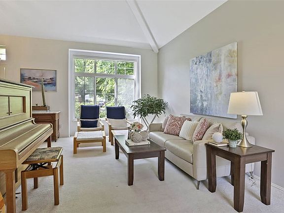 Living room with soaring, vaulted ceiling and freshly painted walls! Check out the dramatic picture window that overlooks the front garden!