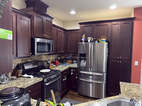 modern kitchen area equipped with a refrigerator, stove and oven, and microwave