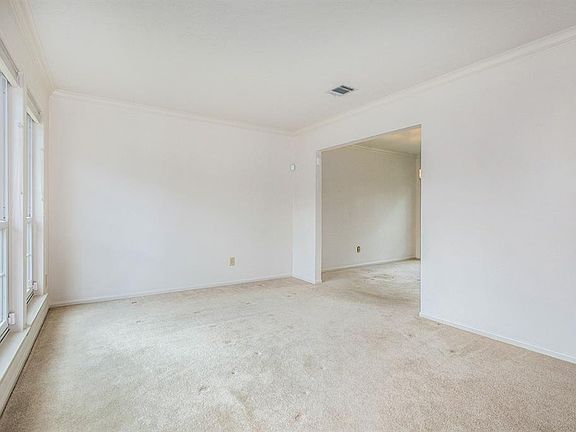 Open the door to a formal living space with crown molding and large picture windows that make this home bright and airy!