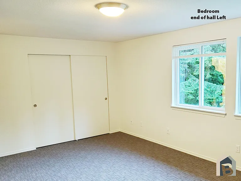 2nd floor large bedroom with view of lawn and mature evergreen trees and double closet