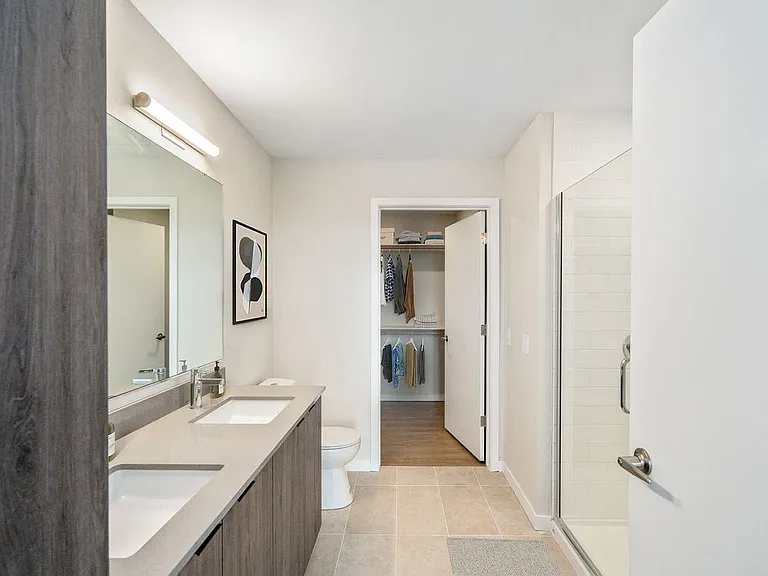 Signature Collection bath with marbled quartz countertop, double vanity, LED lighted vanity mirror, and tile flooring.