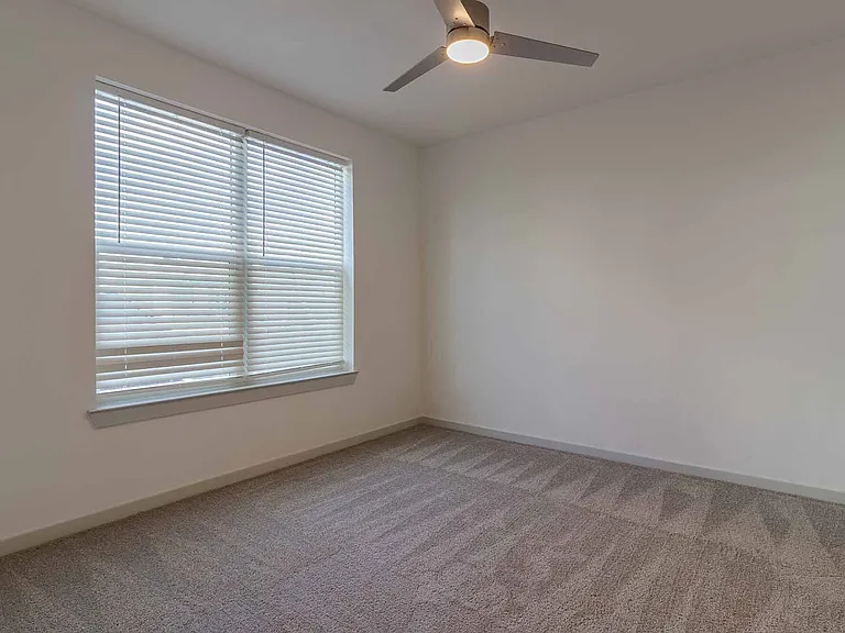 Comfortable carpeted bedroom with a ceiling fan and a large window for plenty of natural light. Comfortable carpeted bedroom with a ceiling fan and a large window for plenty of natural light.