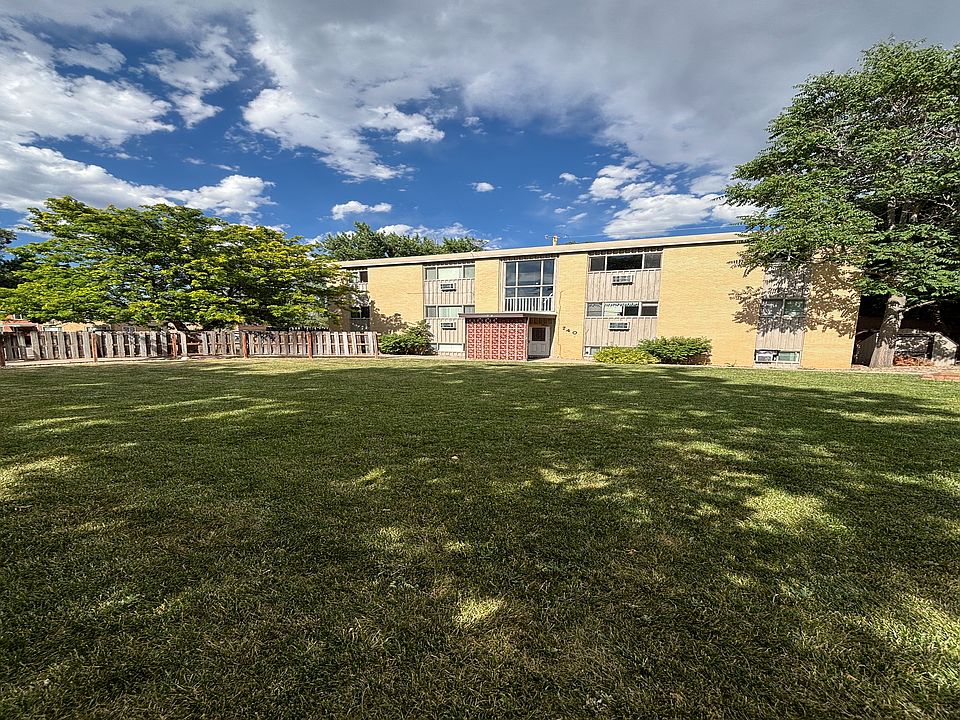 Charming apartment complex with lush green lawn and vibrant trees under a bright blue sky.