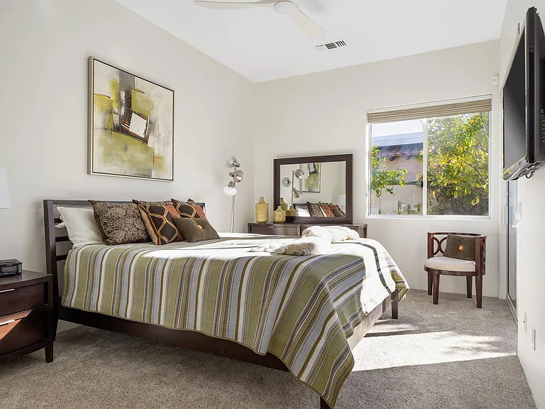 Guest room with king bed and smart TV and patio out to right.