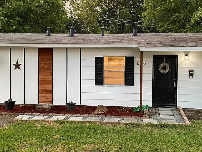 Single-story home exterior with covered entry, updated front door, and low-maintenance landscaping with a paver walkway.