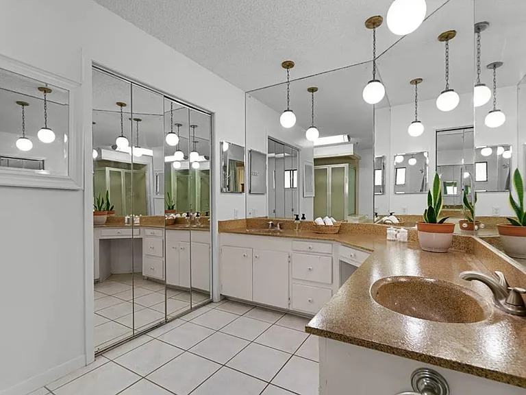 Dual vanities. Walk-in closet behind mirror doors