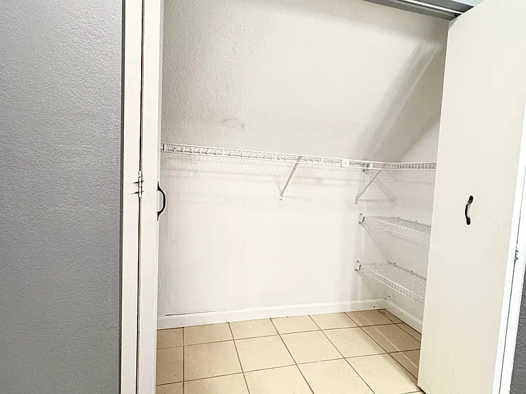 The primary bath features a closet with ample hanging space and shelving for organized clothing storage.