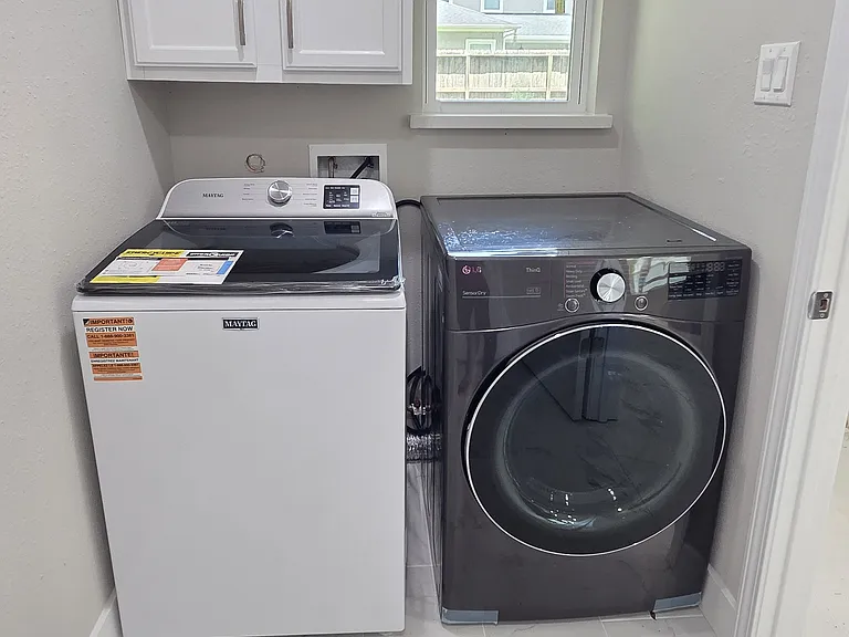 Utility room is in the home! Features white cabinetry above for storage and a window for natural light.